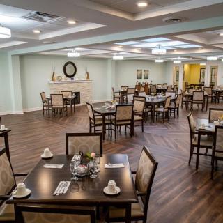 An elegantly designed dining area with multiple tables and chairs, featuring a wooden floor and stylish lighting.