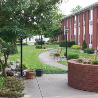 A well-maintained garden path in an apartment complex with lush greenery and brick buildings.