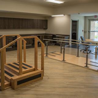 A well-equipped rehabilitation room featuring a set of parallel bars and a wooden ramp designed for physical therapy exercises.