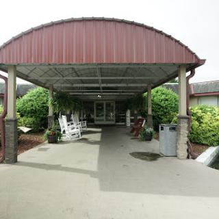 A welcoming entrance to a building, featuring a covered walkway and rocking chairs.