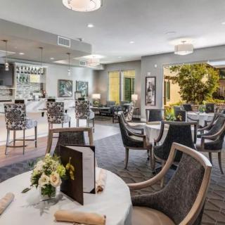 An elegantly designed restaurant dining area with tables set for service, featuring floral arrangements and a modern aesthetic.