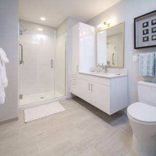 A modern, minimalist bathroom with sleek white fittings and a spacious shower area.