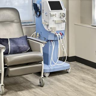 A comfortable patient chair beside a dialysis machine in a healthcare setting.