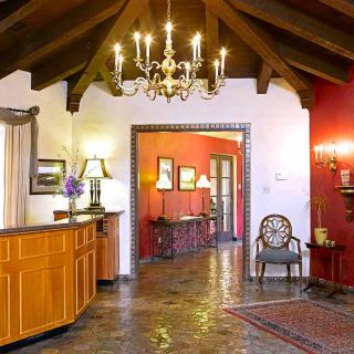A traditional lobby area with a chandelier, wooden beams, and elegant furniture.
