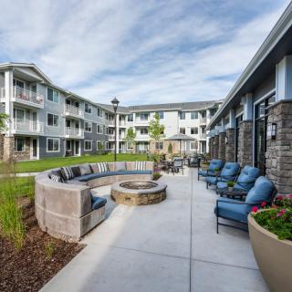 A modern apartment complex featuring a landscaped courtyard with seating and a fire pit.