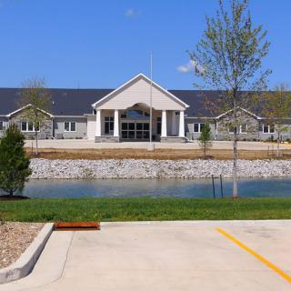 A modern building with a pond in the foreground, set against a clear blue sky.