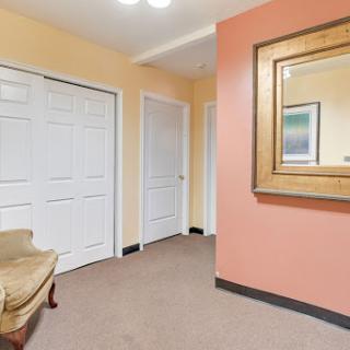 A welcoming hallway featuring a decorative mirror and multiple doors leading to different rooms.