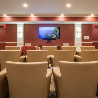 A small theater room with rows of comfortable chairs facing a large screen.