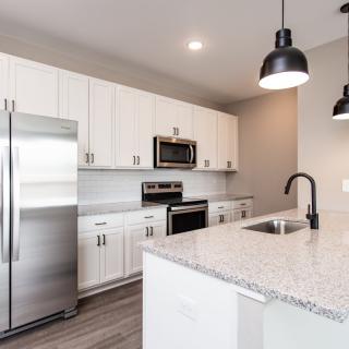 Modern kitchen with white cabinets and stainless steel appliances.