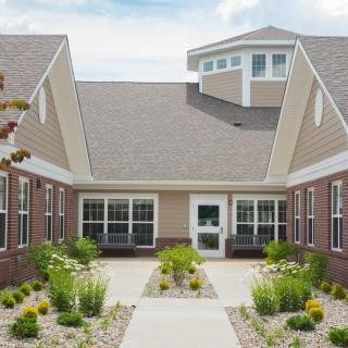 A modern residential building with landscaped gardens and a central pathway.