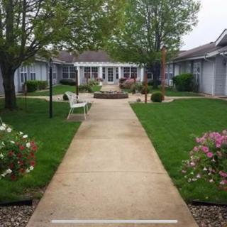 A serene courtyard featuring a central walkway surrounded by lush greenery and seating areas.