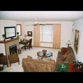 A cozy living room with a fireplace, sofa, and coffee table, complemented by a television and elegant decor.