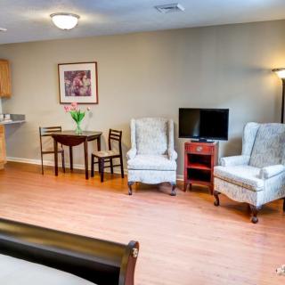 A cozy living room with elegant chairs, a small dining table, and a television.
