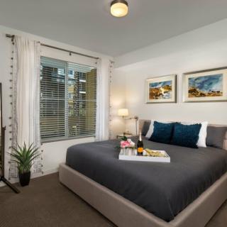 A modern bedroom with a stylish bed and elegant decor featuring artwork and a window view.