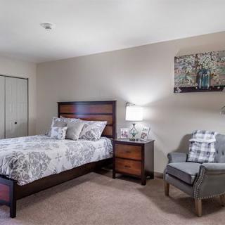 A cozy bedroom with a wooden bed, nightstand, and a comfortable chair.