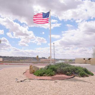 A vibrant American flag waving against a backdrop of clouds and a vast sky.