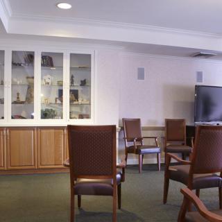 A spacious meeting room with chairs arranged around a television and display shelves.