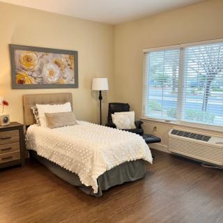 A cozy bedroom with a single bed, nightstand, and artwork on the wall.