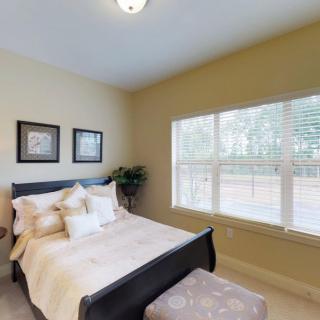 A cozy bedroom with a neatly made bed and large window providing natural light.