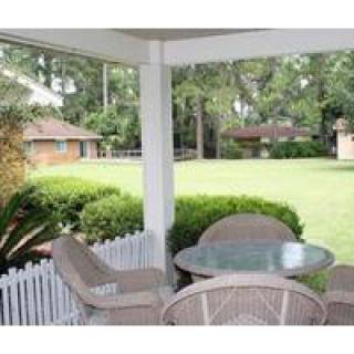 A cozy patio with wicker furniture overlooks a lush garden.