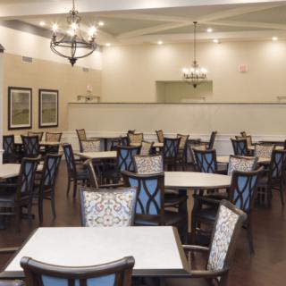 A spacious dining room with neatly arranged tables and chairs under elegant lighting.