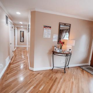A cozy hallway with wooden flooring and a small table featuring a lamp and mirror.
