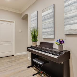 A modern entrance featuring a digital piano, elegant artwork on the walls, and a touch of greenery.