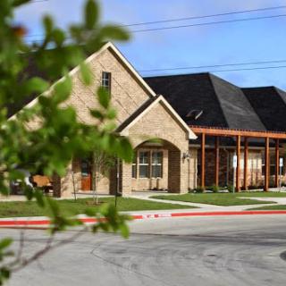 A charming residential building with a blend of stone and modern architecture, surrounded by landscaped greenery.
