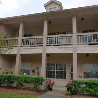 A two-story apartment building with balconies and landscaped surroundings.