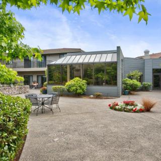 A spacious backyard patio featuring a sunroom and lush greenery.
