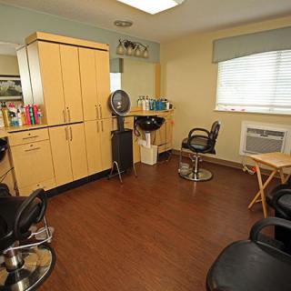 A cozy hair salon with chairs, a hair dryer, and wooden cabinets.