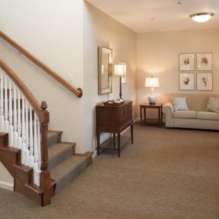 A cozy living room featuring a staircase, sofa, and elegant lighting.