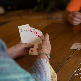 Two people playing a card game at a wooden table.