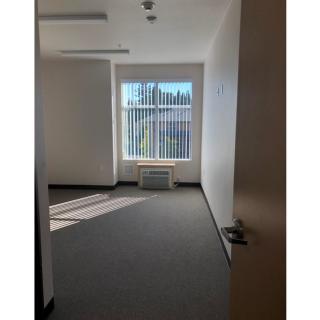 A vacant office space with sunlight streaming through a large window.
