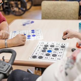 Seniors playing bingo at a table in a leisure setting.