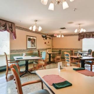 An indoor dining area with neatly arranged tables and chairs, featuring elegant lighting and decor.