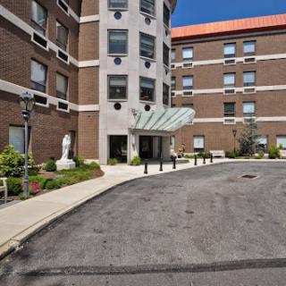 A welcoming entrance to a residential building, featuring well-maintained landscaping and a clear blue sky.