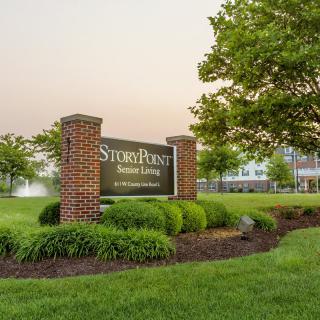 A welcoming sign for a senior living community surrounded by well-maintained greenery and trees.