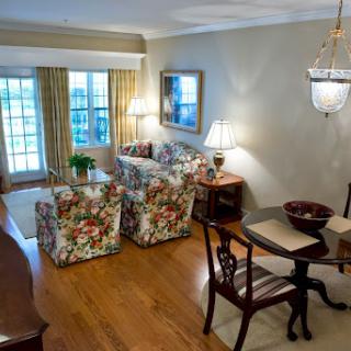 A cozy and elegantly decorated living room with floral-patterned furniture, a dining area, and ample natural light.