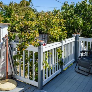 A sunny backyard deck with a white fence and outdoor seating.