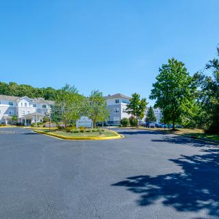 A spacious parking lot in front of residential buildings under a clear blue sky.