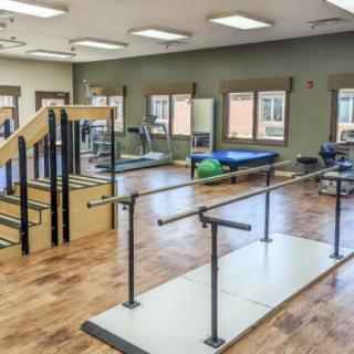A rehabilitation center equipped with various physical therapy tools, including parallel bars and a staircase for mobility exercises.