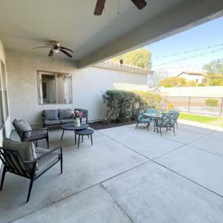 A spacious outdoor patio area with comfortable seating and a ceiling fan, perfect for relaxation.
