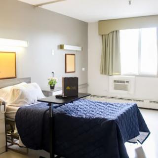 A well-lit hospital patient room featuring a neatly made bed and modern furnishings.