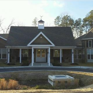 A residential building with a central entrance and surrounding trees.