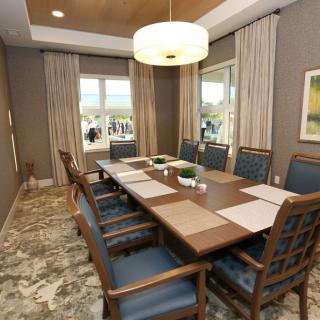 A modern conference room with a large table and elegant chairs, featuring neutral tones and natural light.