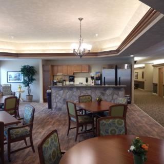 A cozy dining and kitchen area featuring a chandelier, seating, and warm lighting.
