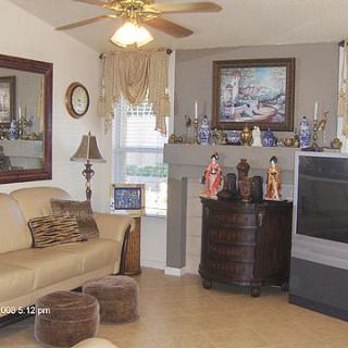 A cozy living room featuring a sofa, large mirror, television, and decorative items on the fireplace mantel.