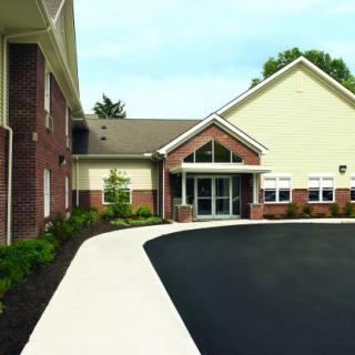 A modern building entrance with a curved pavement and landscaped surroundings.
