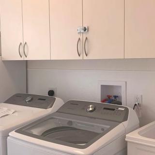 A laundry room featuring a washing machine and dryer beneath overhead cabinets.